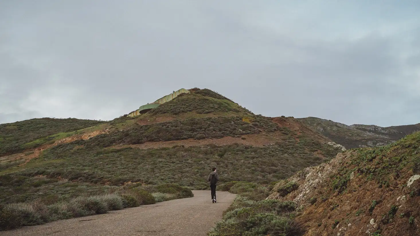 A jaded man riding an electric scooter into the wilderness.