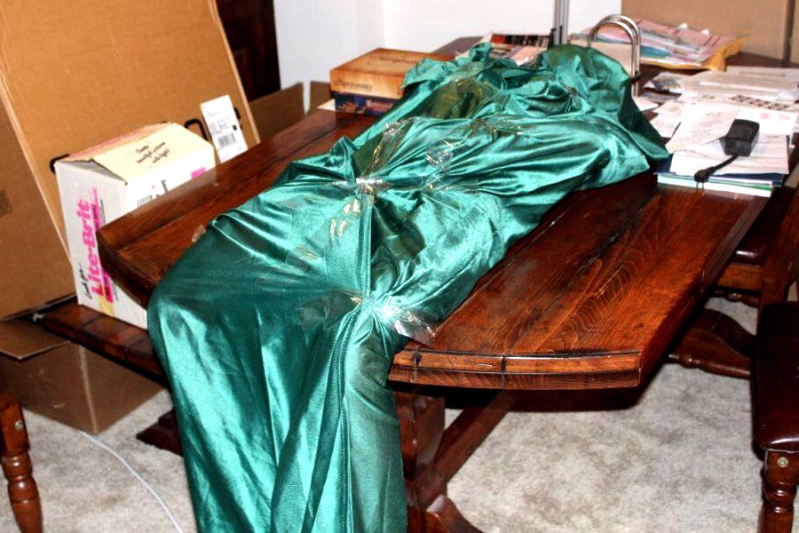 A damaged real doll wrapped in a teal blanket on a table.
